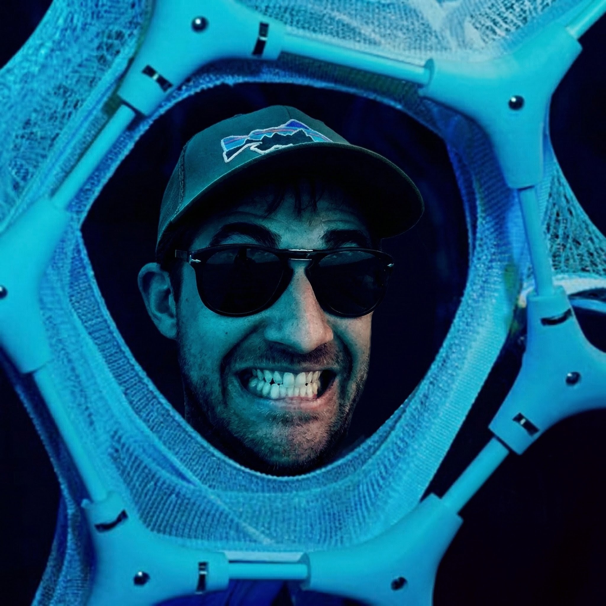 a headshot photograph of Dan Romero wearing very expensive sunglasses while standing on a court